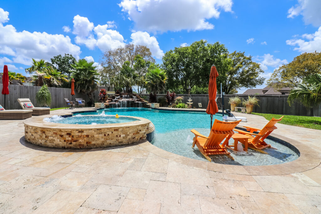 An in-ground spa and pool with a waterfall feature by Southern Charm Pools.